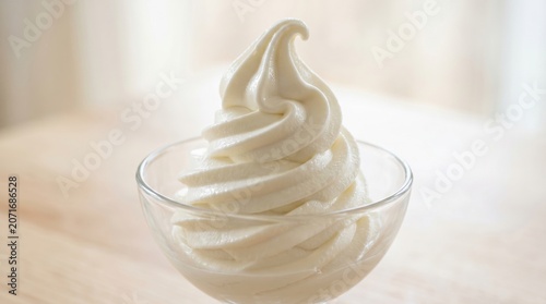 Swirl of creamy vanilla soft serve ice cream in glass bowl. Cold frozen dairy dessert for refreshing summer snack. Sweet treat served in cafe. Gourmet food photography close up.