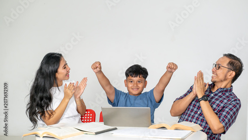 Proud Asian Parents Applauding Son Cheering with Raised Arms in Front of Laptop