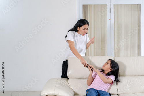 Angry Asian Mother Confiscating TV Remote Control From Her Disobedient Daughter