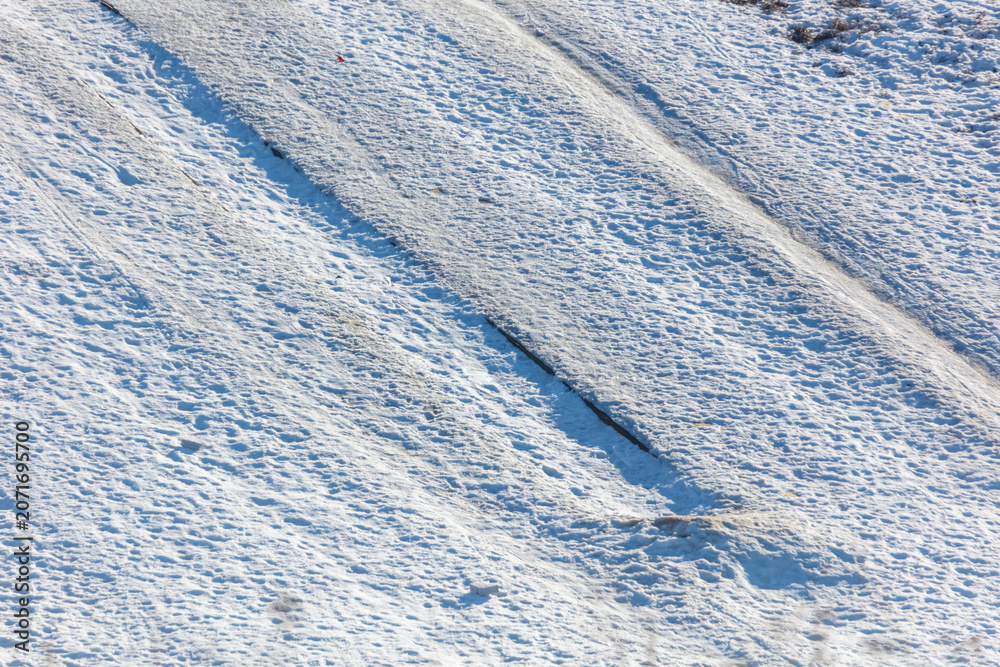 Fototapeta premium Snow blankets a field, showing deep tire tracks