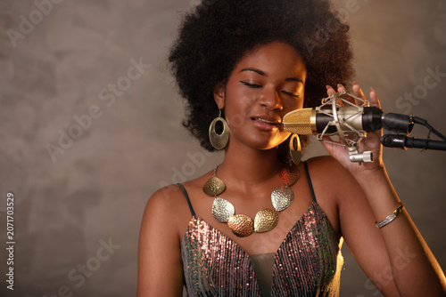African female singer with an Afro hairstyle, wearing a beautiful, long, elegant dress, is enjoying the music she is singing.