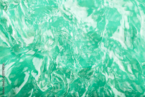 Turquoise water background. Clear turquoise water surface displaying gentle ripples and reflections, illuminated by bright sunlight, vibrant and dynamic visual effect in natural setting