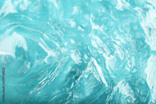 Blue water background. Clear turquoise water surface displaying gentle ripples and reflections, illuminated by bright sunlight, creating serene and tranquil aquatic environment