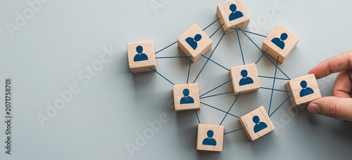 Wooden blocks with human icons connected by lines showing teamwork and network collaboration.