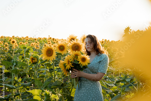 a young girl in a field of sunflowers holds a bouquet of sunflower flowers and walks on a sunny day