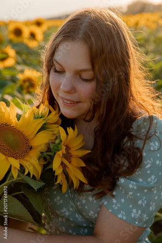 a young girl in a field of sunflowers holds a bouquet of sunflower flowers on a sunny day	
