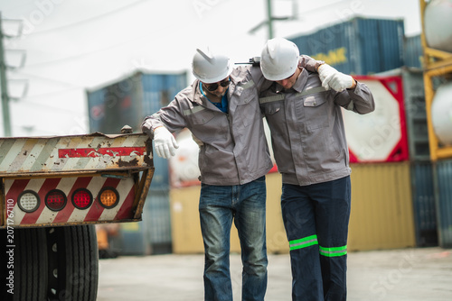 Foto Senior worker shows signs of heat exhaustion while younger coworker provides support near truck trailer