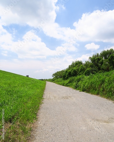 初夏の梅雨晴れの江戸川河川敷の砂利道風景