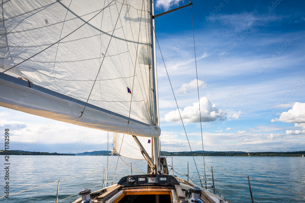 Fototapeta premium Sailing on a calm lake with a clear sky and gentle breeze in the afternoon sun