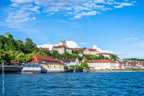 View from the water showing the town of Meersburg on Lake Constance with buildings on the hillside under a blue sky