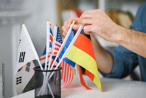Focus on different countries flags on table and man s hands