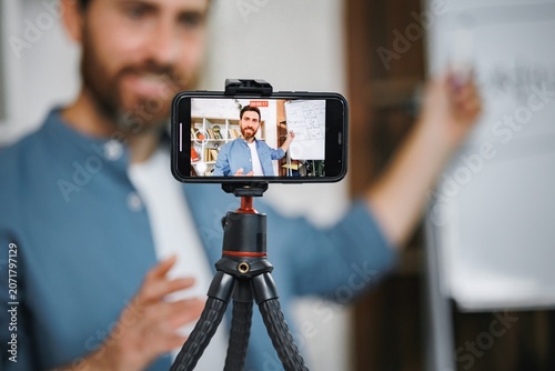 Focus on a phone screen recording a man tutor explaining rules of foreign language