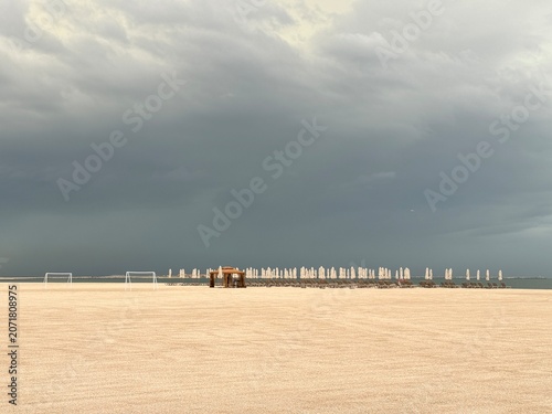 Moody coastal landscape of a resort beach with football goals under dark clouds, Dubai, UAE