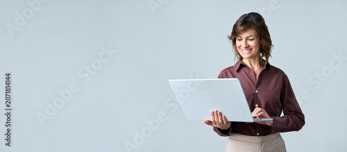 Valokuva Latin mid-age businesswoman holding laptop, looking at screen standing on background isolated
