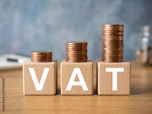 Vat tax concept with wooden blocks and copper coins on a desk in an office