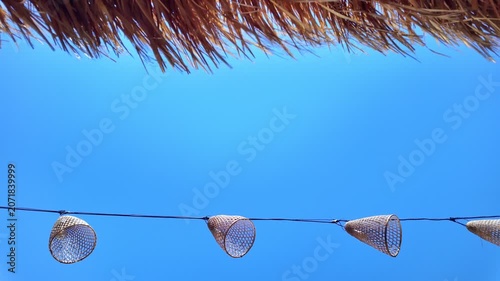 Handmade lanterns and straw wicker swaying in wind create charming atmosphere. Perfect for cozy, decorative and outdoor themes, copy space, slow motion