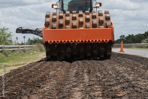 Canvastavla Front view of a heavy padfoot soil compactor roller flattening a dirt surface on a road construction site