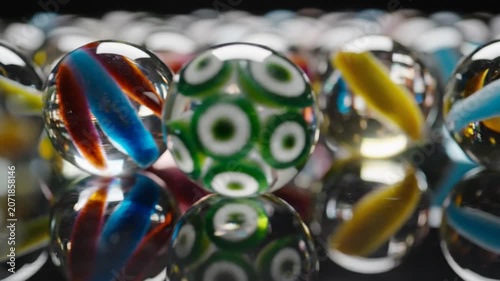 Glass marbles lined up on reflective surface.