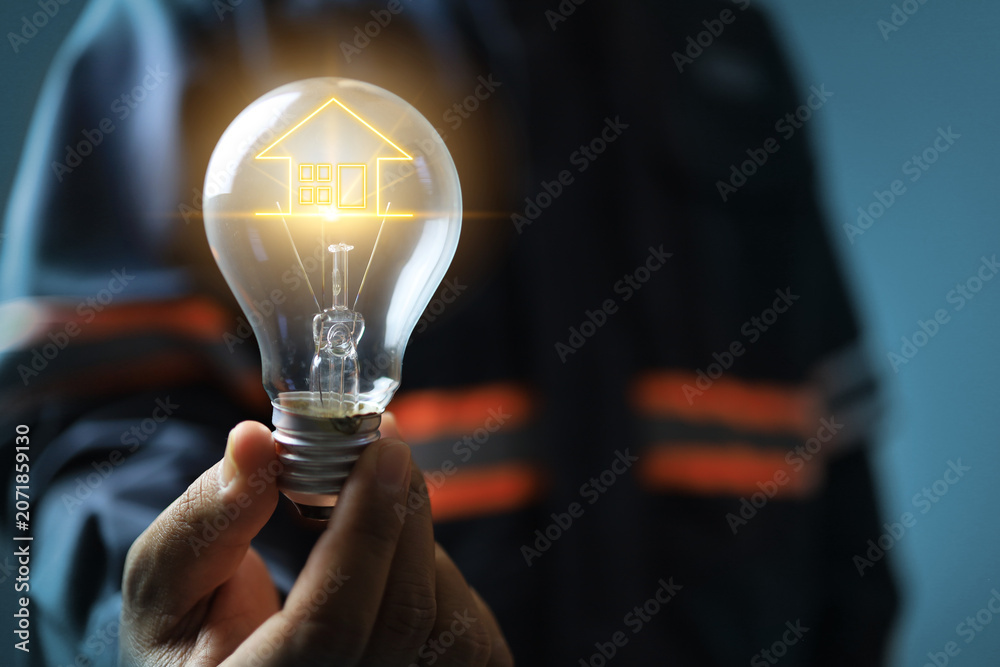 Fototapeta premium energy saves concept with engineer holding light bulb as filament house icon represents encourage people to electricity save