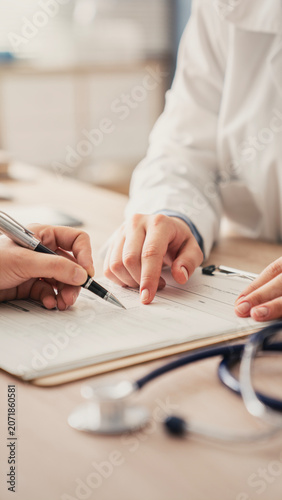 Patient signs papers under the guidance of a medical practitioner