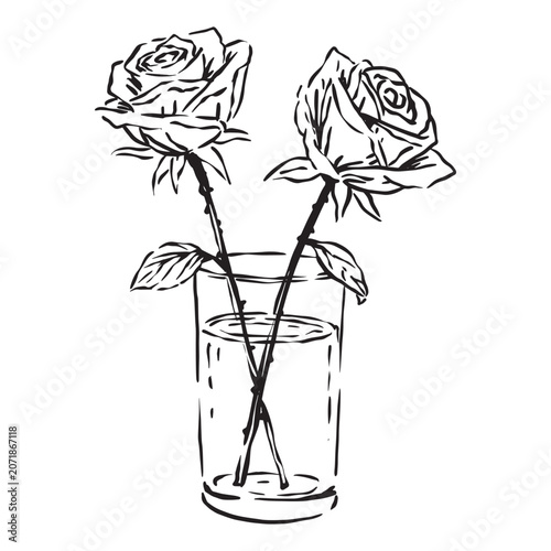 Two roses are placed in a glass vase on a table indoors.