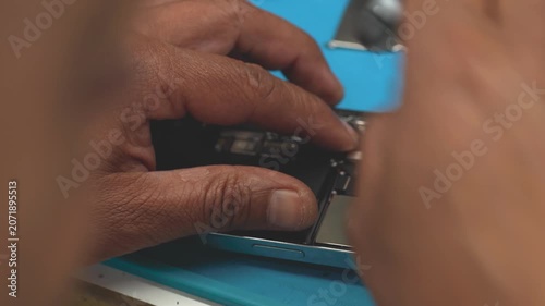 Technician repairing smartphone close-up in electronics repair workshop