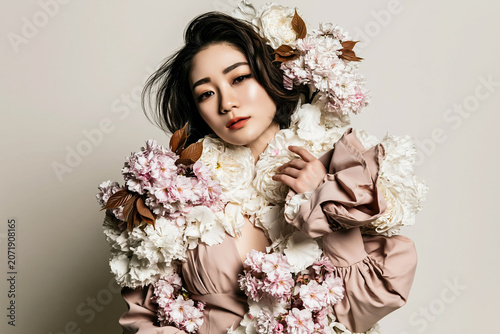 Beautiful woman with colorful flowers in her hair creating a vibrant and elegant natural portrait with soft fashion aesthetic.