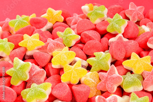 Assorted colorful gummy candies and lollipop on red background. Top view. Jelly  sweets.