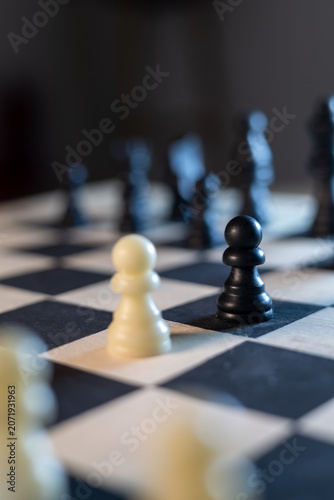 Fotografie Black and White Chess Pawns Facing Each Other on Chessboard
