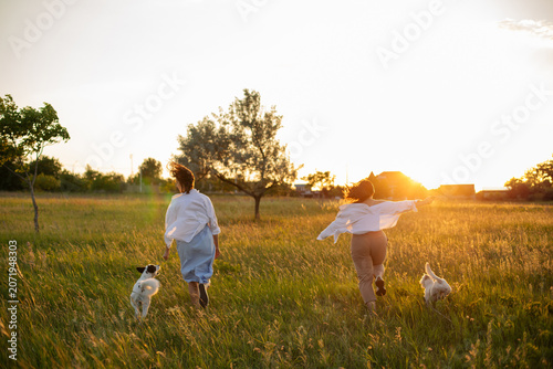 Photography Happy women running with dogs on green meadow at sunset wide banner