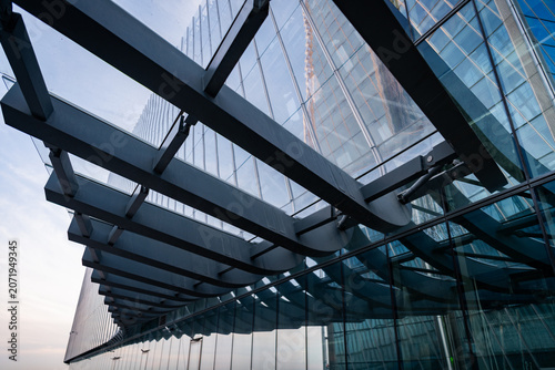Modern glass skyscraper facade with metal canopy. Architectural design of business center tower.