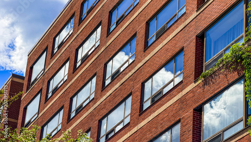 Building exterior with windows reflecting clouds in urban setting
