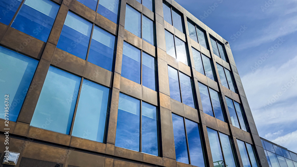 Obraz premium Building with large windows reflecting the sky in a city setting during daytime