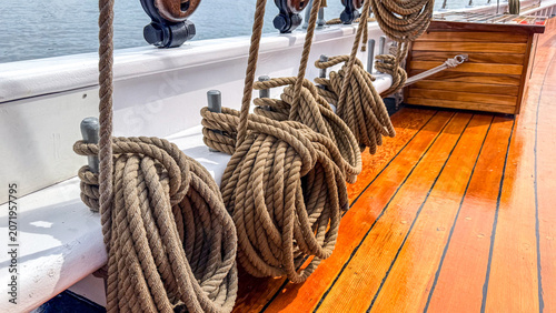 Ropes coiled on a wooden deck of a boat in a clear water setting