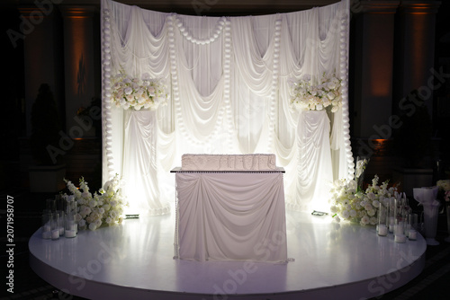 Schilderij op canvas Elegant stage with white drapery, flowers and cake table prepared for a wedding celebration