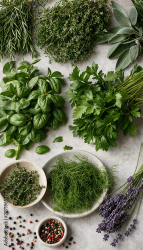 Assorted fresh culinary herbs spices and edible flowers on white marble surface with culinary ingredients rosemary lavender peppercorns seasoning aromatic vegetarian fragrant nutrition