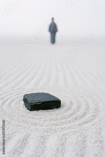 A dark rock anchors an empty sand garden under soft light