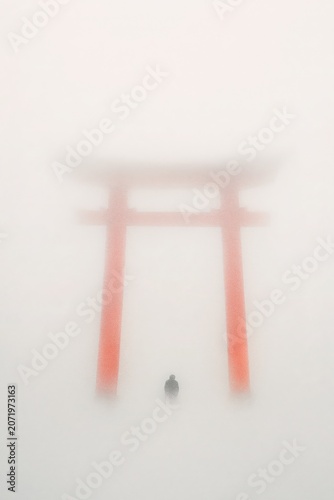 The quiet path beneath the red torii in endless morning mist