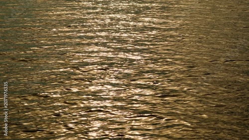Reflection of sunlight on the water surface of the lake at dusk at sunset. The water surface. The sun's rays twinkle on the water.	