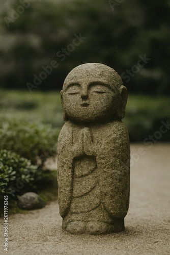 Ancient carved stone figure praying with closed eyes in a quiet garden