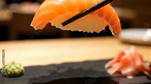 Enjoying sushi at a restaurant with salmon nigiri served on a black plate