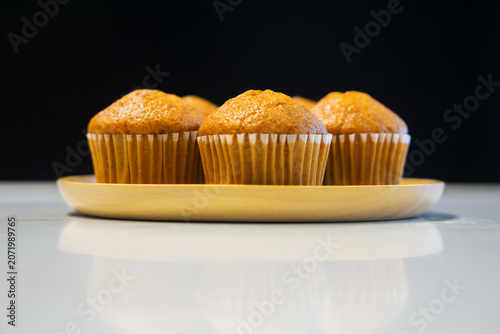 Banana nut muffins cupcakes lined up on a wooden plate.