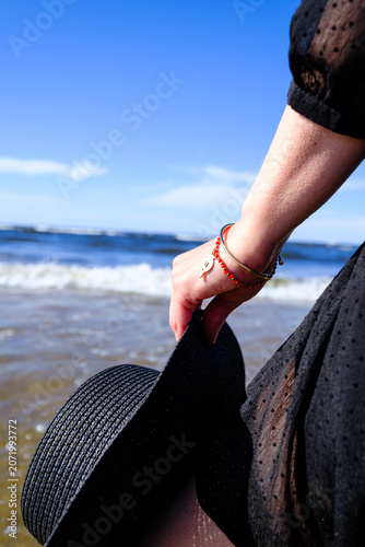 Close-up of woman holding black hat by the sea