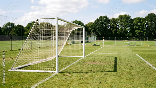 Fotografie Empty soccer goal post on a sunlit training field with green grass