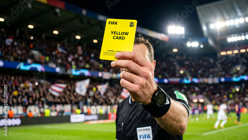 Photos Close up of a soccer referee hand holding up a yellow card in a stadium