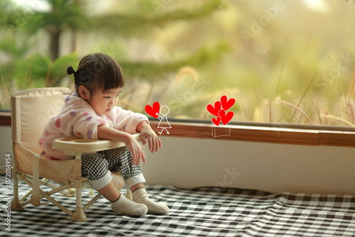 Adorable Toddler Imagining Cartoon Doodles While Sitting by Window.