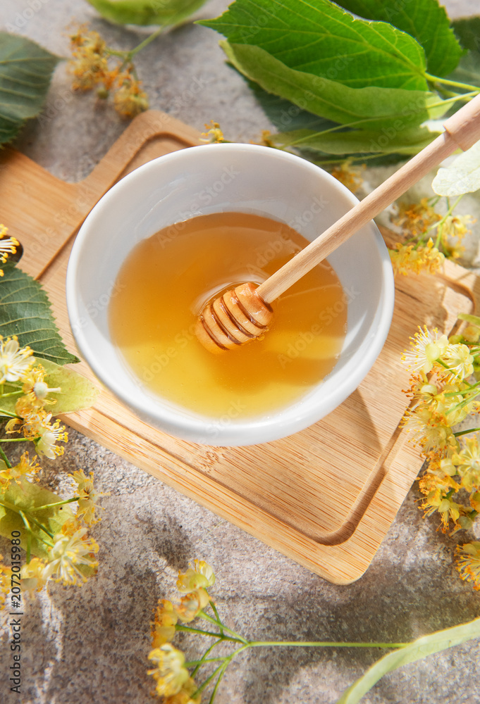 Fototapeta premium Linden honey in bowl with dipper and flowers