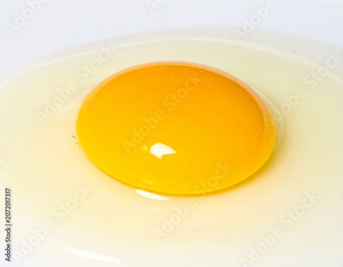 Cracked Fresh Chicken Egg with Golden Yolk Flowing on White Surface
