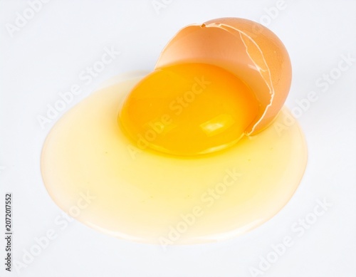 Cracked Fresh Chicken Egg with Golden Yolk Flowing on White Surface