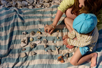 Child and mother collecting seashells on the beach